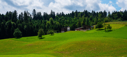 View of farm house and barn in rural area in Switzerland. Concept of organic agriculture. Colorful summer rural view of farmland. Fields and wonderful blue sky.