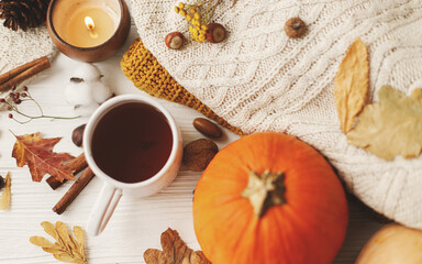 Fototapeta na wymiar Autumn flat lay. Warm tea, pumpkins, cozy knitted sweaters, autumn leaves and candle