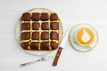 Homemade chocolate pie cheesecake and cup of coffee cappuccino on white wooden table. Top view.