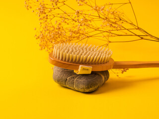 Zero waste dry massage wooden brush on yellow background. Reusable accessory for beauty routine, plastic free concept