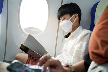 15 year old boy reading a book on airplane