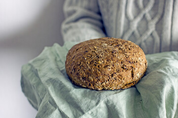 Gluten free homemade bread in the hands of a man without a face in a gray sweater, copy space