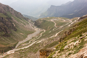 The mountain road from Rohtang Pass to Manali winding down the green hills of a Himalayan valley.