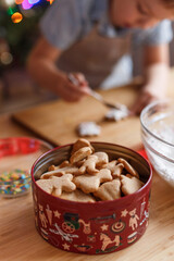 The child decorates New Year's gingerbread cookies on a wooden table. New Year and Christmas concept.