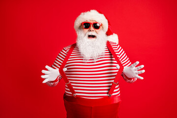 Fototapeta na wymiar Portrait of his he nice handsome attractive comic childish cheerful cheery grey-haired Santa wearing gloves having fun pulling suspenders isolated over bright vivid shine vibrant red color background