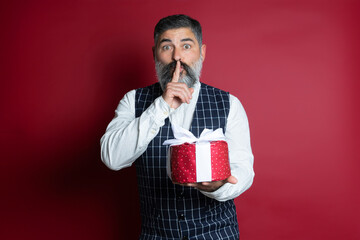 Portrait of hipster man with a gift making a surprise gesture over red background