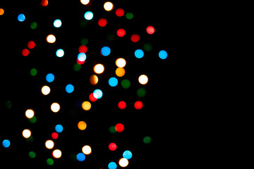 Multi-colored glares side on a black background with room for copyspace text. Festive New Year's background bokeh