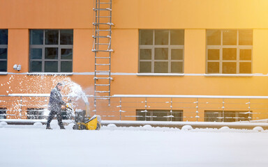 Worker with track drive snowblower removing deep snow, heavy duty assistant for snow and ice...
