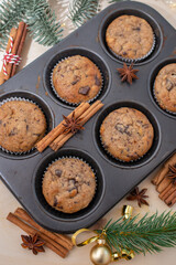 Fresh homemade gingerbread muffins in baking form on wooden table with Christmas decoration