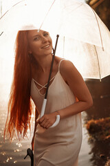 red-haired girl in a white dress with an umbrella after the rain