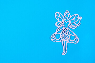 The figure silhouette of the fairy angel on the blue background of the flat lay. Christmas opening in a minimalist style with a place for text.