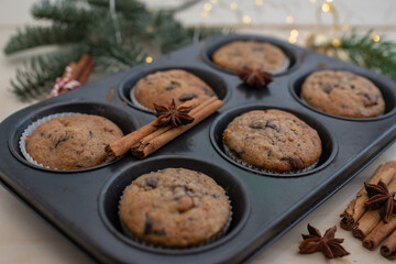 Fresh homemade gingerbread muffins in baking form on wooden table with Christmas decoration