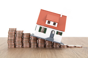 Declining dollar coins and small house model on the table