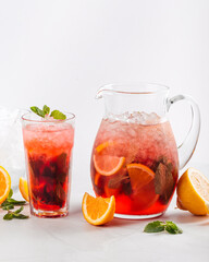 Side view on red berry lemonade in a jug and glass