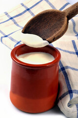 Pot de crème fraîche avec une cuillère en bois et un torchon a carreaux en gros plan