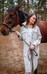 Girl rider standing next to the horse. The girl holds the horse's bridle