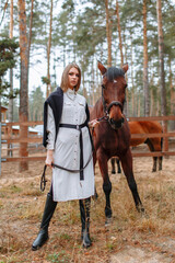 Girl rider standing next to the horse. The girl holds the horse's bridle