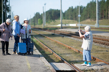 senior women take a photo on a platform waiting for a train to travel during a COVID-19 pandemic