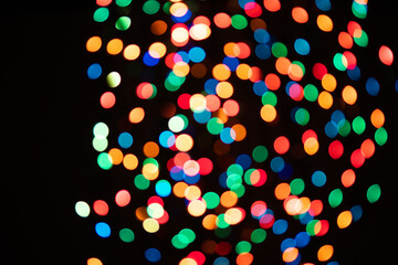 Multi-colored glares side on a black background with room for copyspace text. Festive New Year's background bokeh