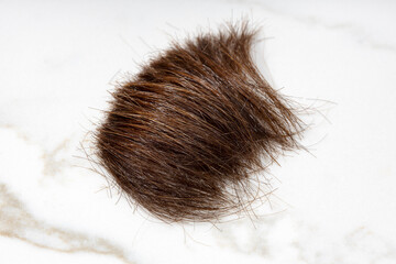 Brown Lock of hair on marble table. Hairstyle or haircut concept