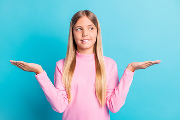 Photo portrait of curious schoolgirl showing copyspaces on hands looking at side isolated on...