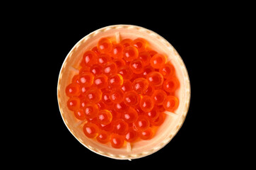 Red caviar tartlets isolated on a black background.