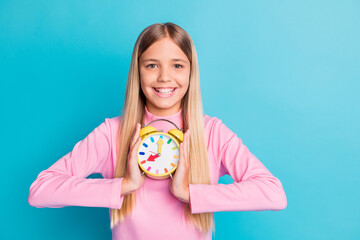 Photo portrait of pretty female preteen keeping colorful clock smiling happily isolated on vibrant turquoise color background