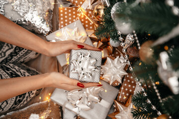 Background with gifts, light bokeh. Woman hands opening gift box. Christmas, new year, birthday concept. Banner, copy space.