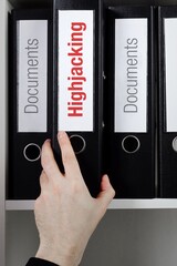 Highjacking. File Folder is taking by a hand from office shelf. Red Text is on the label of the...