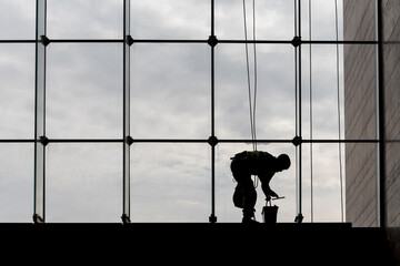 Worker silhouettes cleaning windows from the inside