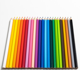 Buntstifte in verschiedene Farben aufgereiht auf weißen Hintergrund