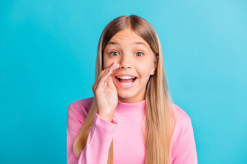 Photo portrait of schoolgirl with blonde hair whispering secret rumor keeping hand near lips isolated on vibrant teal color background