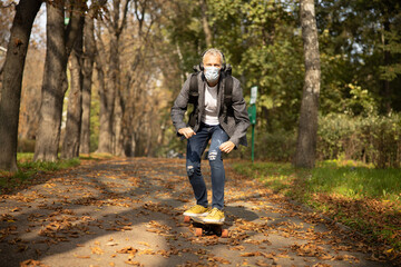 Fototapeta premium Happy mature man rolling skateboard in park