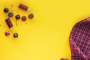 Cloth, threads, pins, buttons and decoration a on yellow background. Flat lay composition with place for text