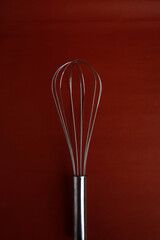 Manual hand blender, Wire whisk, mixing balloon mixer for blending, beating, Egg beater isolated on red background. Metal stainless steel kitcenware utensil