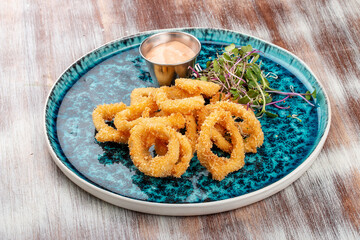 Squid rings fried in batter with sauce on a decorative plate