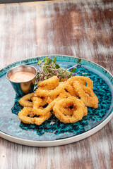 Squid rings fried in batter with sauce on a decorative plate