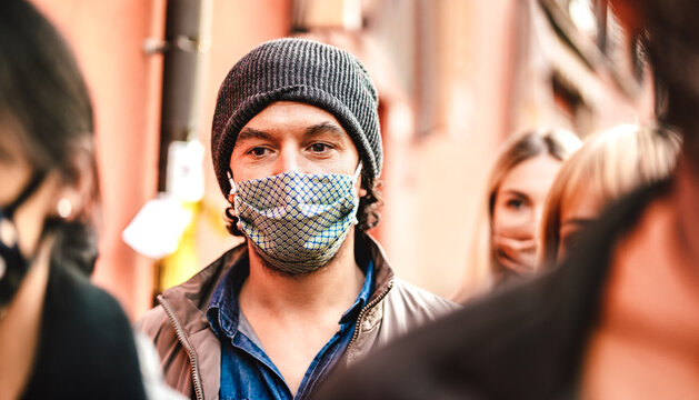 Urban crowd of citizens walking on city street wearing face mask - New normal reality lifestyle concept with people on worried alienated mood - Selective focus on man with hat - Warm contrast filter