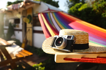 Comfortable hammock with hat and vintage camera near motorhome outdoors on sunny day, closeup