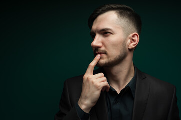 Portrait of pensive young businessman wearing dark formal suit.