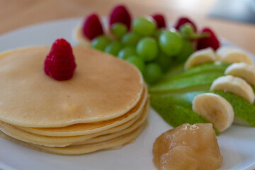 Pancakes mit Obst und Nutella oder Sternen auf einem Teller angerichtet Bunt
