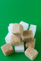 Cube of white and brown sugar on a green background.