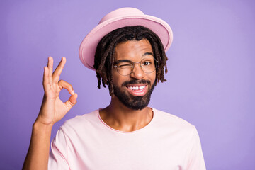 Photo portrait of winking man showing ok-sign isolated on vivid purple colored background