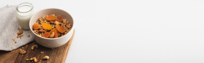 delicious granola with nuts, dried apricots and yogurt on wooden board on white background, banner