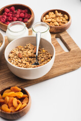 delicious granola with nuts, fruits and yogurt on wooden board on white background
