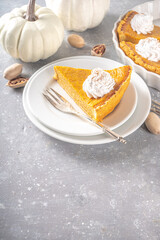 Traditional Autumn Pumpkin Pie. Homemade American Pumpkin pie topped with Whipped Cream. Rustic wooden table bakcground with Cozy plaid and sweater.