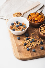 delicious granola with nuts,dried apricots and blueberry on wooden board on white background