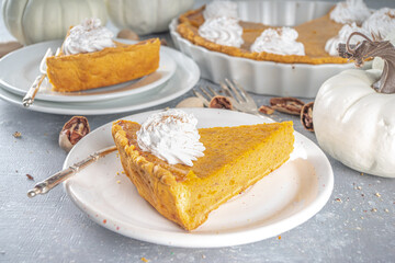 Traditional Autumn Pumpkin Pie. Homemade American Pumpkin pie topped with Whipped Cream. Rustic wooden table bakcground with Cozy plaid and sweater.
