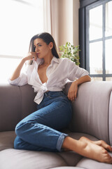Obraz premium Girl posing beautifully in the studio. Posing while sitting on the couch. 
