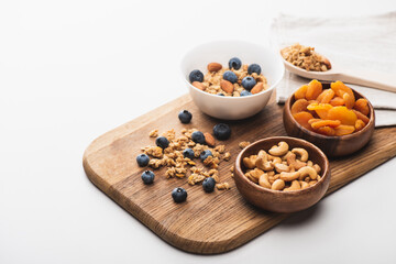 delicious granola with nuts,dried apricots and blueberry on wooden board on white background